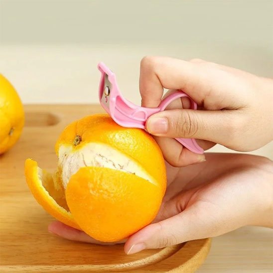 Eplucheur rose en inox épluchant une orange