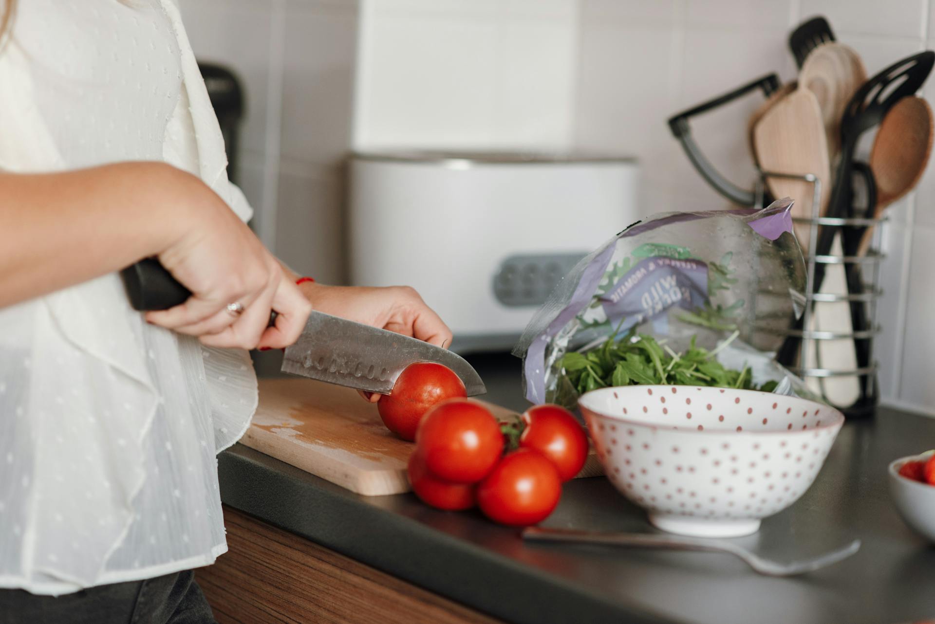 femme coupant des tomates sur une planche a decouper dans sa cuisine